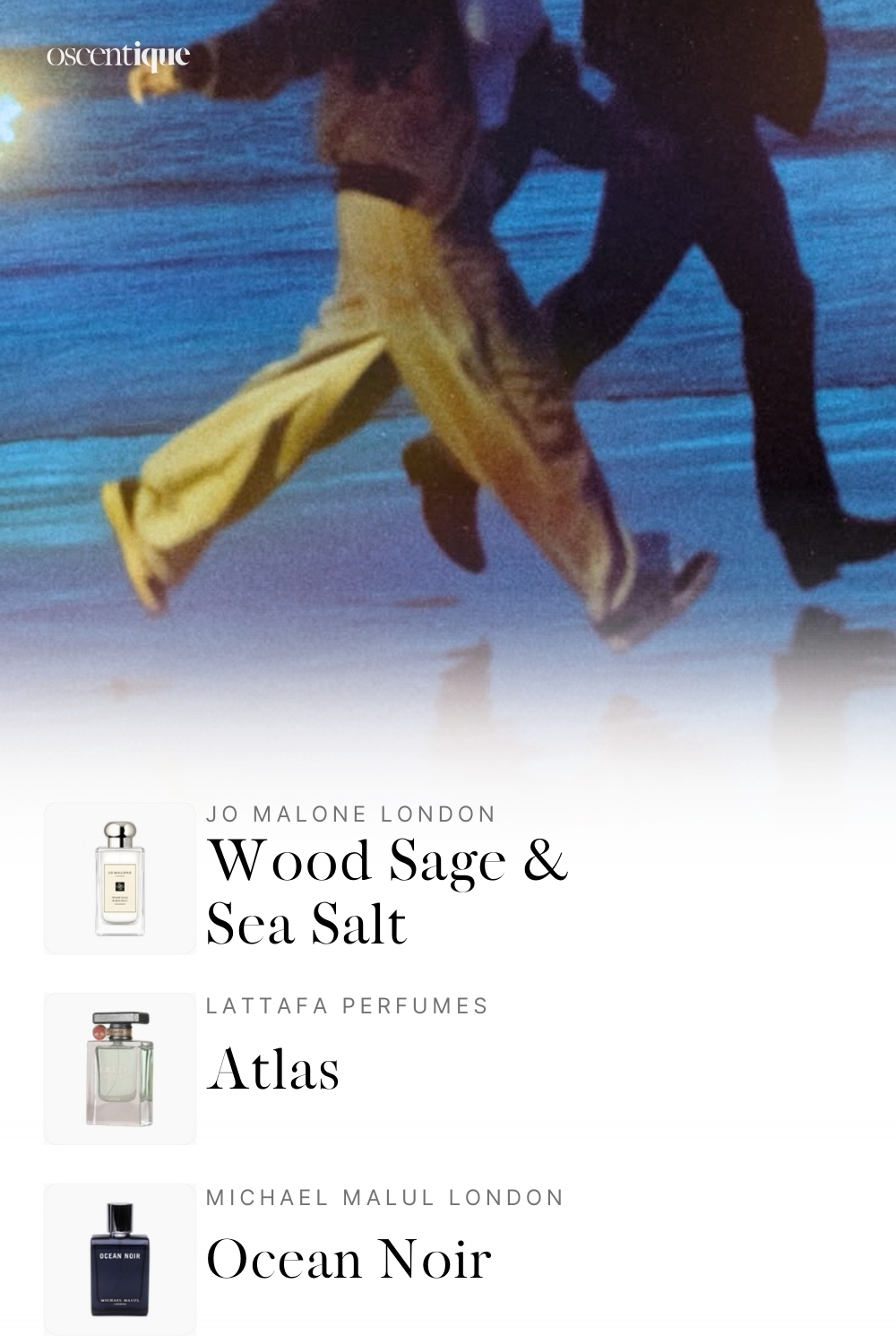 Two people run along a shoreline at dusk holding a torch, casting warm reflections onto the blue water. The mood is energetic and coastal. Featured fragrances: Maison Margiela Sailing Day, Natura Kaiak Aero, Antonio Banderas King of Seduction Absolute.
